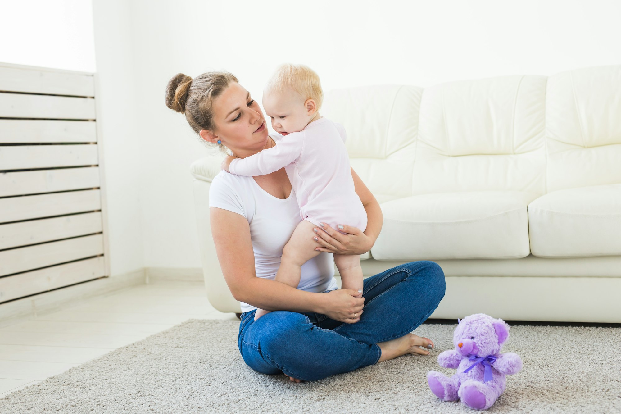 Young happy loving mother and her baby daughter is playing. Maternal care. Childcare